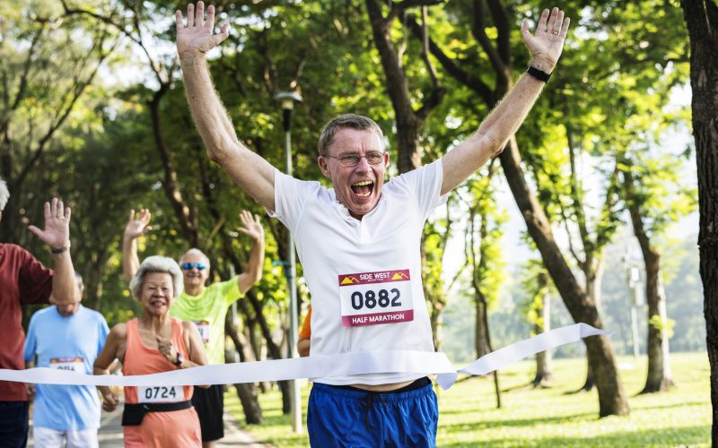 Happy senior running through the finish line