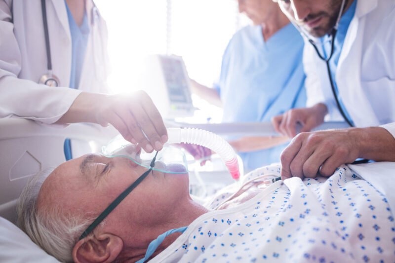 pikwizard-team-of-doctors-putting-oxygen-mask-on-a-male-senior-patient-face